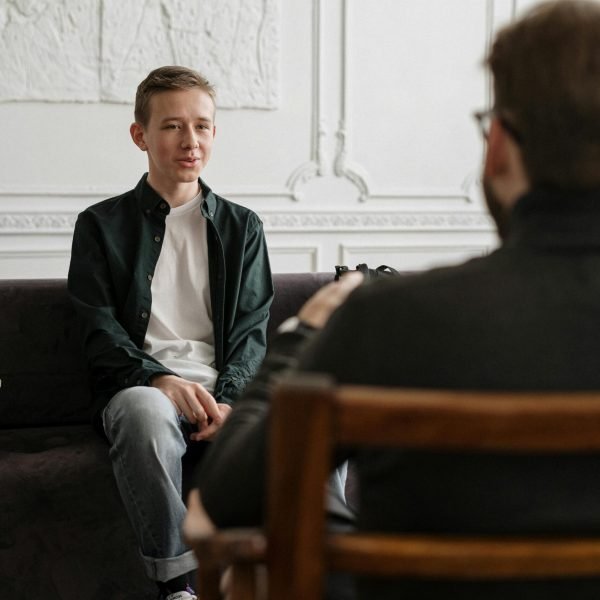 A teenager sits across from a counselor in a therapy session, promoting mental health awareness.